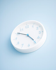 Minimalistic white wall clock on a blue background. Time concept. Vertical with copy space.