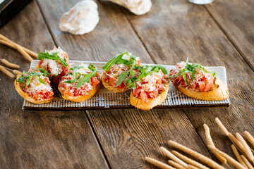 Salmon bruschettas with grated cheese and arugula on the wooden background