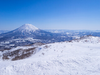 Fototapeta na wymiar Looking at ski resort and snowy volcano on a clear day in early spring (Niseko Mt.Resort Grand Hirafu, Hokkaido, Japan)