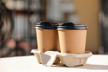Takeaway cups of tasty latte on table outdoors, closeup