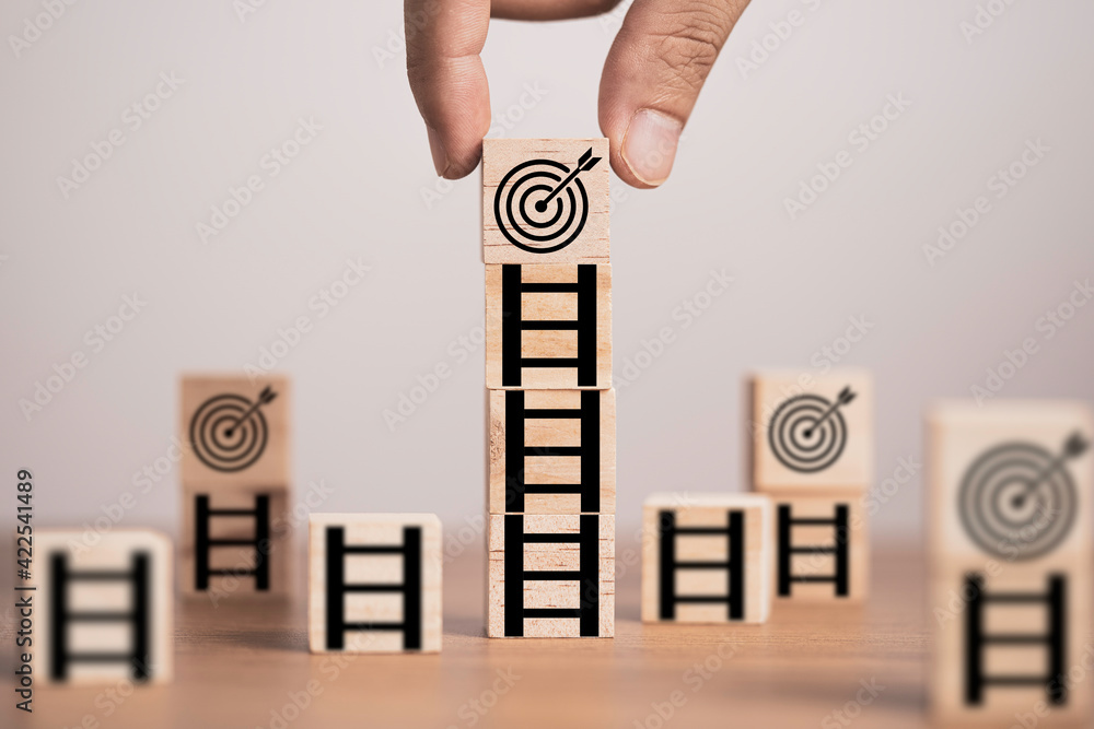 Poster hand putting target board on the top of ladder which print screen on wooden cube block, setup challe