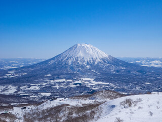 Snowy volcano on a clear day in early spring (Niseko Mt.Resort Grand Hirafu, Hokkaido, Japan) - obrazy, fototapety, plakaty