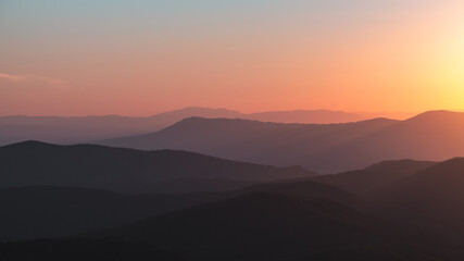 Fototapeta premium A panorama of a vibrant orange, yellow, blue sunset over the layers of the Appalachian Mountain range from Shenandoah National Park, Virginia, USA.