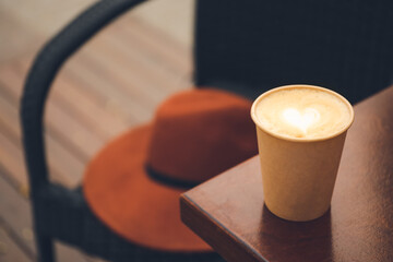 Takeaway cup of tasty latte on table in cafe, closeup