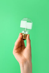Female hand with light bulb on color background