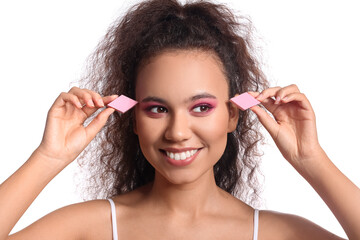 Beautiful young African-American woman with makeup sponges on white background