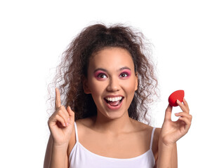 Beautiful young African-American woman with makeup sponge on white background