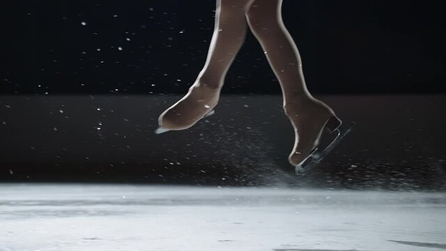 legs of female figure skater during jumps, closeup of skates on ice, training or performing champion, slow motion