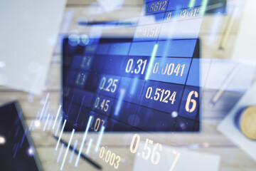 Multi exposure of abstract financial graph and modern digital tablet on desktop on background, top view, financial and trading concept