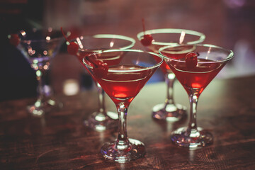 View of different coloured alcohol beverage cocktail drinks setting on bar counter in the night club party, tequila, glasses with martini, vodka, spritz and others on decorated catering banquet table
