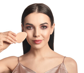 Beautiful young woman with makeup sponge on white background