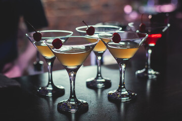 View of different coloured alcohol beverage cocktail drinks setting on bar counter in the night club party, tequila, glasses with martini, vodka, spritz and others on decorated catering banquet table
