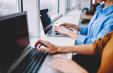 Unrecognizable women sharing media files using bluetooth connection on modern netbooks, cropped...
