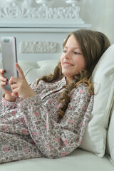 Naklejka premium Portrait of Beautiful little girl with tablet pc on sofa