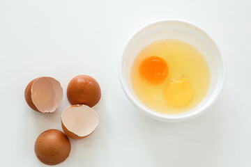 raw broken chicken eggs and broken shells. egg yolks in a white plate