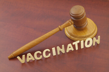 Wooden judge gavel and word vaccination on table. Law and vaccination concept.