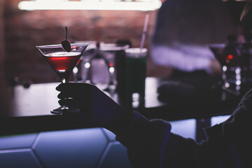 View of different coloured alcohol beverage cocktail drinks setting on bar counter in the night club party, tequila, glasses with martini, vodka, spritz and others on decorated catering banquet table
