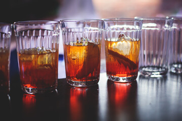View of different coloured alcohol beverage cocktail drinks setting on bar counter in the night club party, tequila, glasses with martini, vodka, spritz and others on decorated catering banquet table