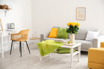 Vase with beautiful yellow roses on table in interior of room