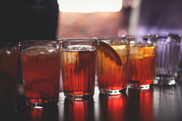 View of different coloured alcohol beverage cocktail drinks setting on bar counter in the night club party, tequila, glasses with martini, vodka, spritz and others on decorated catering banquet table