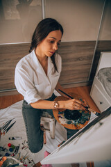 Beautiful talented female artist painting at her home.