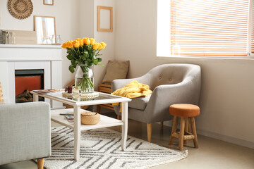 Vase with beautiful yellow roses on table in interior of room
