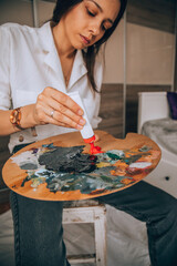 Beautiful talented female artist painting at her home.
