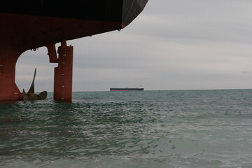 Stern of a cargo ship aground against backdrop of blue sea. At Stern ship Propeller with rudder....