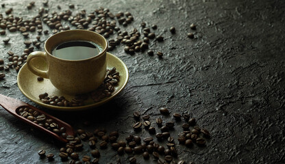 Hot black coffee for morning beverage menu in vintage brown ceramic cup with coffee beans roasted in burlap sack bag on dark grunge rustic table background. Flat lay with copy space.