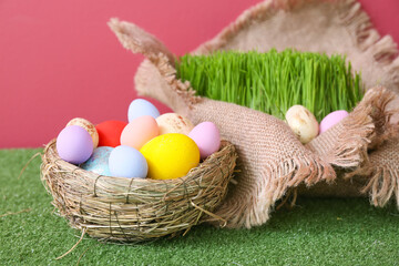 Beautiful Easter eggs on grass against color background