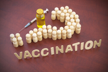 People (wooden figures) shaped as question mark, vaccine bottle, syringe and word vaccination....
