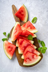 Ripe and juicy watermelon slices on wooden board and light background
