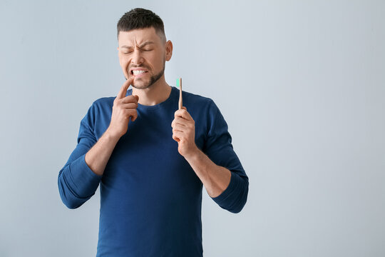 Man With Aching Teeth And Brush On Grey Background