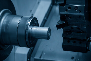 The  CNC lathe machine cutting the metal shaft parts. The hi-technology metal working processing by CNC turning machine .