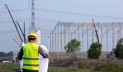 Asian construction workers check drawings plan blueprint at construction site