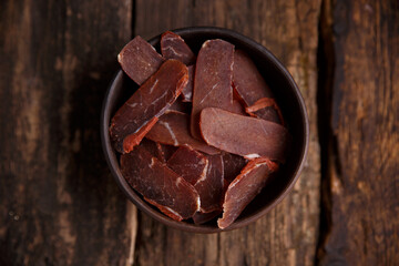 jerky in a bowl on a dark background, top view