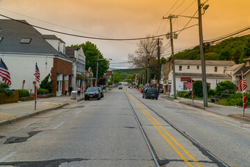 Exterior view down generic main street in small town USA as sunrise comes over illuminating sky beautiful orange colors in background