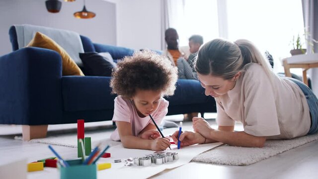 Mother with small daughter drawing pictures, multi ethnic family and home office.