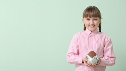 Cute little girl with chocolate Easter egg on color background
