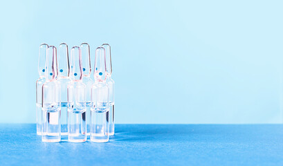 Glass medical ampoules on the table on a blue background. Medical glass ampoules.