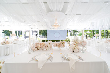 Festive wedding table setting with flowers, napkins, cutlery, glasses, bright summer table decor. Wedding decor