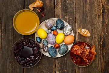 Getting ready for Easter, coloring eggs with natural dyes. Bowls with natural turmeric, hibiscus, onions. Wood background