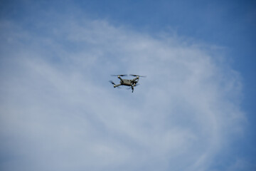 small Black drone with cloudy blue sky background