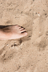 a man's foot on the sand. Summer beach season