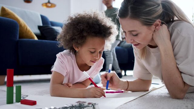 Mother with small daughter drawing pictures, multi ethnic family and home office.