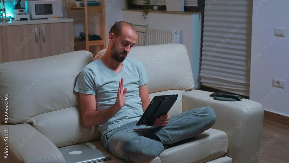 Poster focused man with beard sitting on couch in front of television while talking with teammates during o