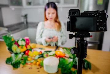 Asian woman blogger or content creator cooking and recording video camera. showing healthy food while recording with camera at kitchen.