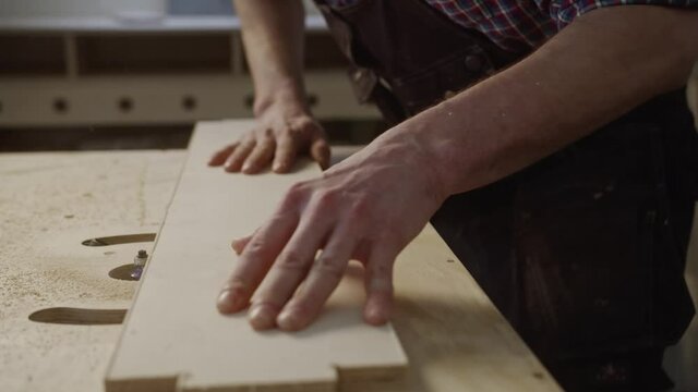 Carpenter mills the edge of the wooden board on the milling machine, manufacturing of wooden products, master works with timber, 4k 60p Prores 422 10 bit