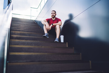 Sportive man resting after training on stairs