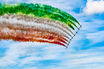 colorful acrobatic airshow of a team of pilots flying jets on formations with colorful smokes venting from the plane.
